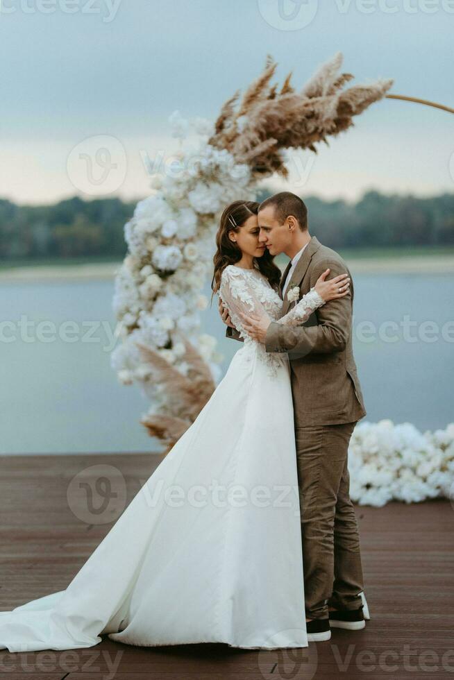 the first wedding dance of the bride and groom on the pier near the river photo