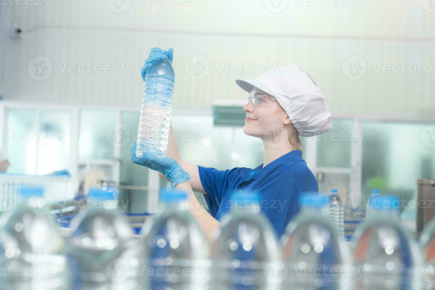 joven contento mujer trabajador en fábrica comprobación agua galones antes de envío. foto