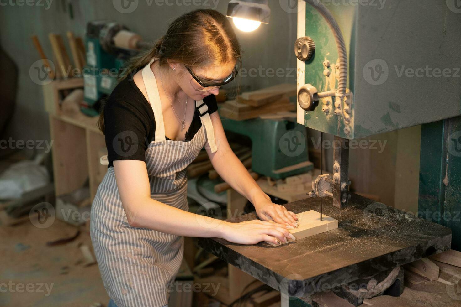 hembra carpintero vistiendo protector la seguridad lentes y utilizando eléctrico trabajo en un madera. artista o mueble diseñador trabajando en un producto idea en un taller. foto