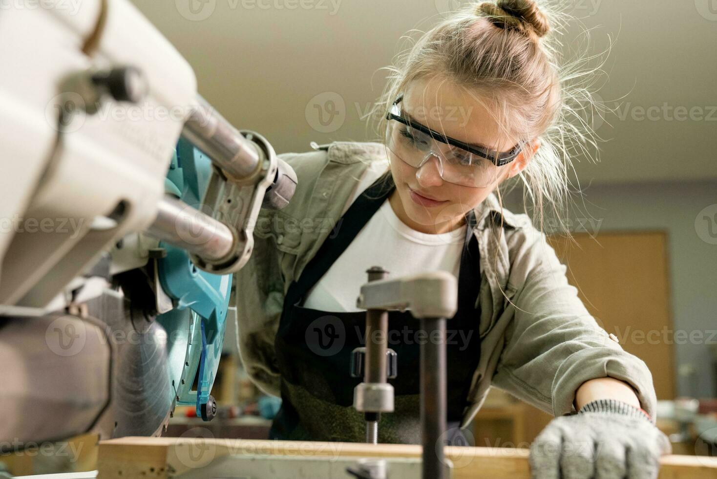 Female Carpenter Wearing Protective Safety Glasses and Using Electric Work on a Wood. Artist or Furniture Designer Working on a Product Idea in a Workshop. photo