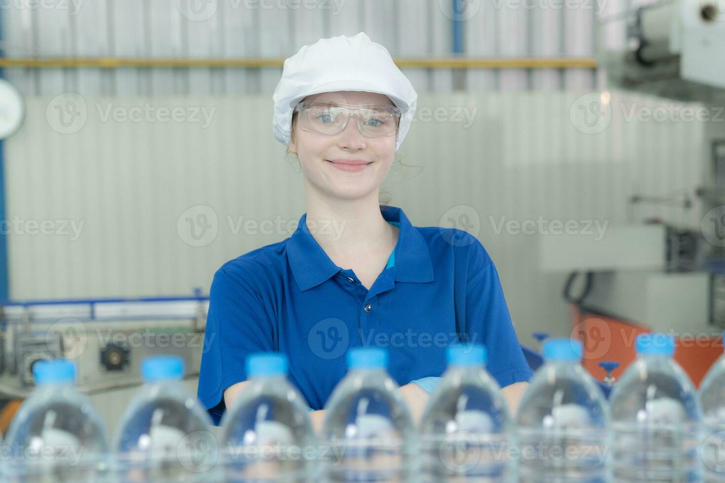 joven contento mujer trabajador en fábrica comprobación agua galones antes de envío. foto