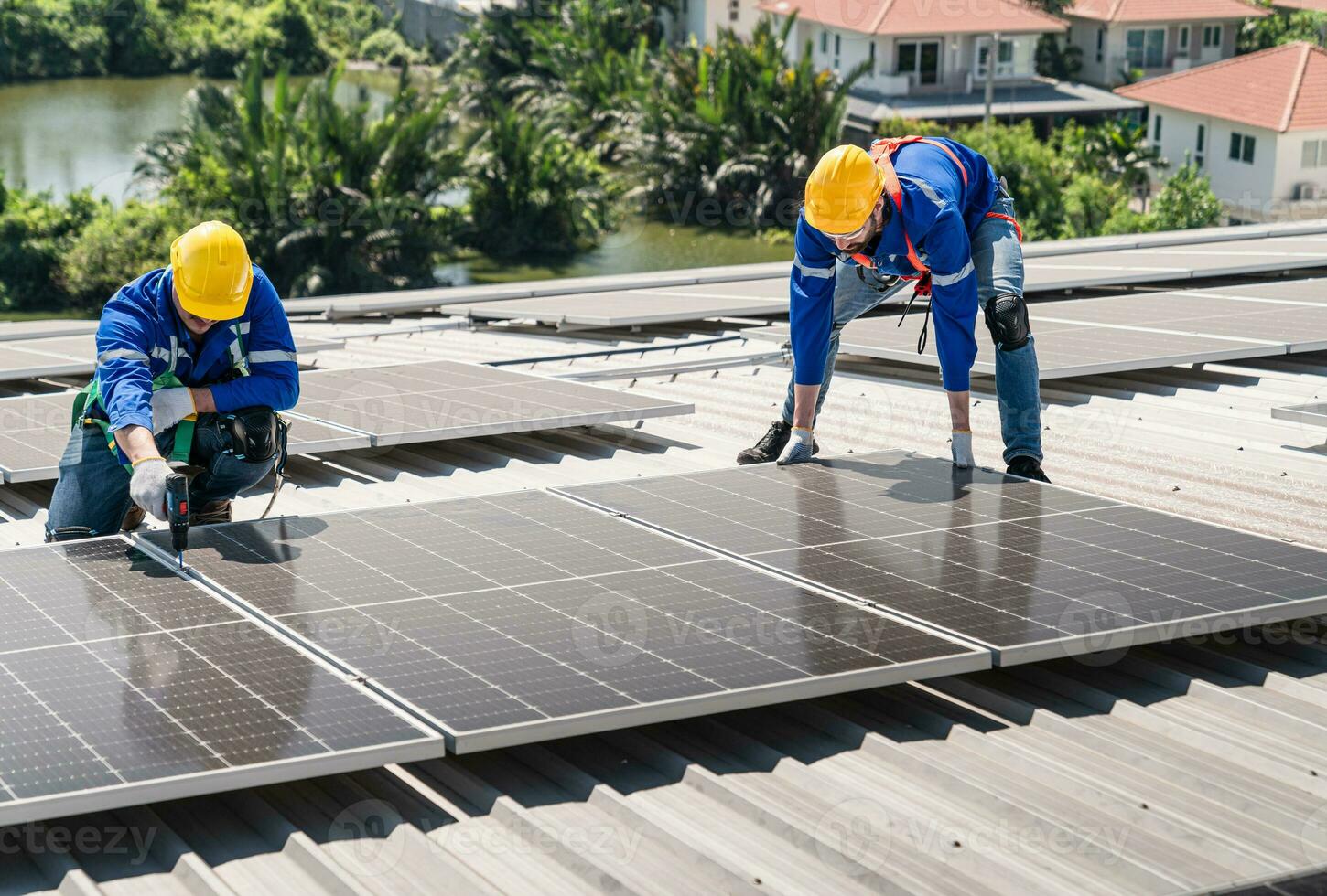 Men technicians carrying photovoltaic solar modules on the factory roof. Engineers in helmets installing solar panel systems outdoors. Concept of alternative and renewable energy. photo
