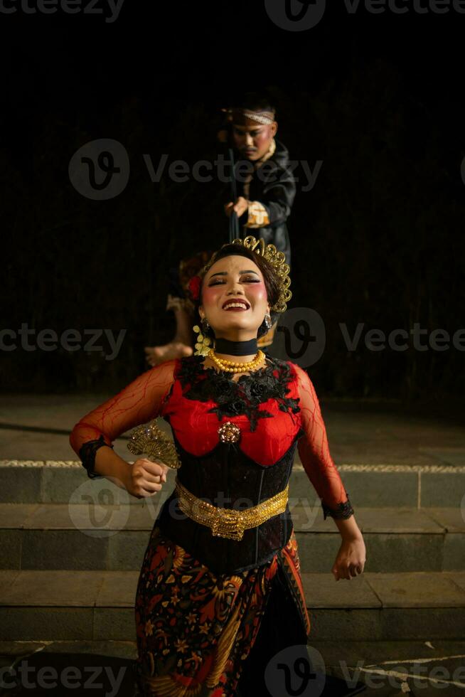 female dancers tied by black scarves while being held by men with sad expressions photo