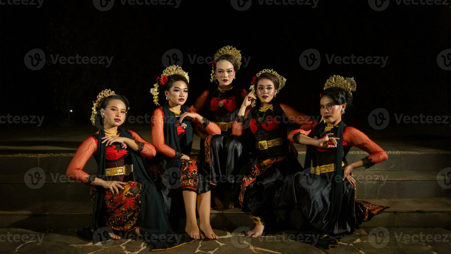 a group of dancers attract attention in striking red costumes and sit together photo