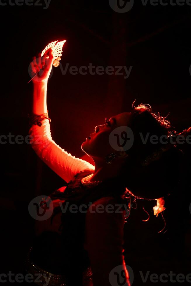 silueta de un hembra bailarín participación joyería en el medio de el quietud de el noche con rojo ligero foto