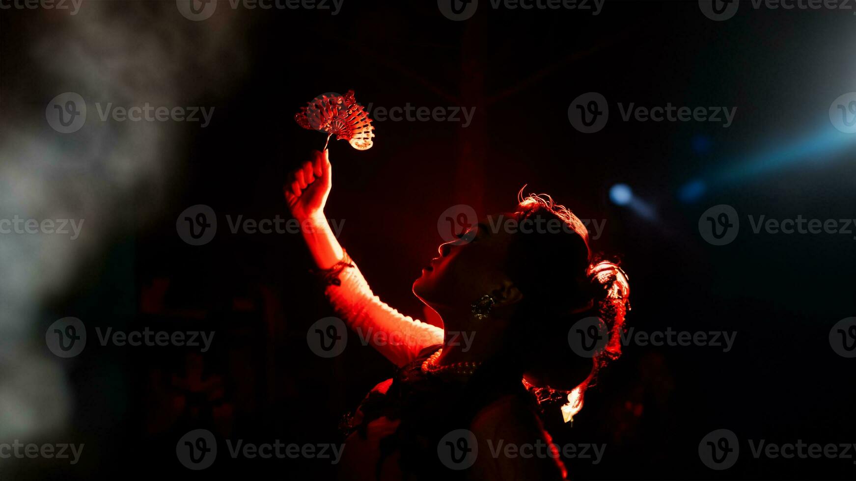 the silhouette of a female dancer holding jewelry shines brightly around the flames and looks bold in the dark photo