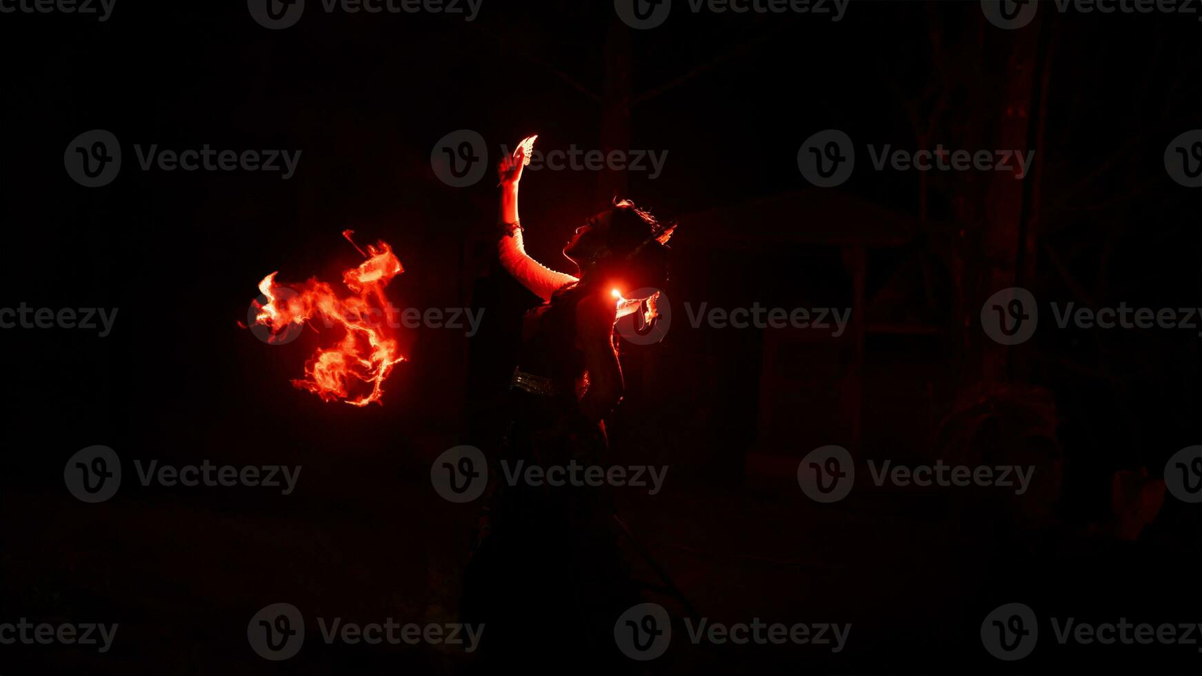 el silueta de un hembra bailarín participación joyería en el oscuro de noche es iluminado por el ligero de un ardiente fuego foto