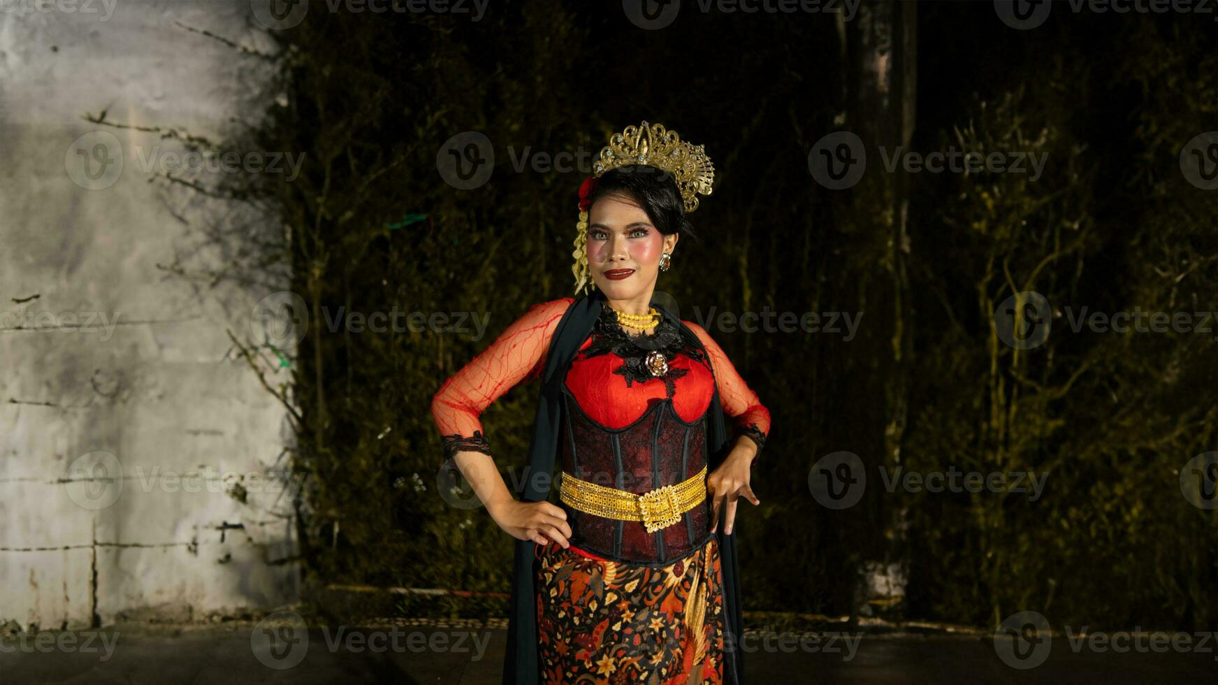 a Balinese dancer wearing gold jewelry and dancing with confidence on the stage photo
