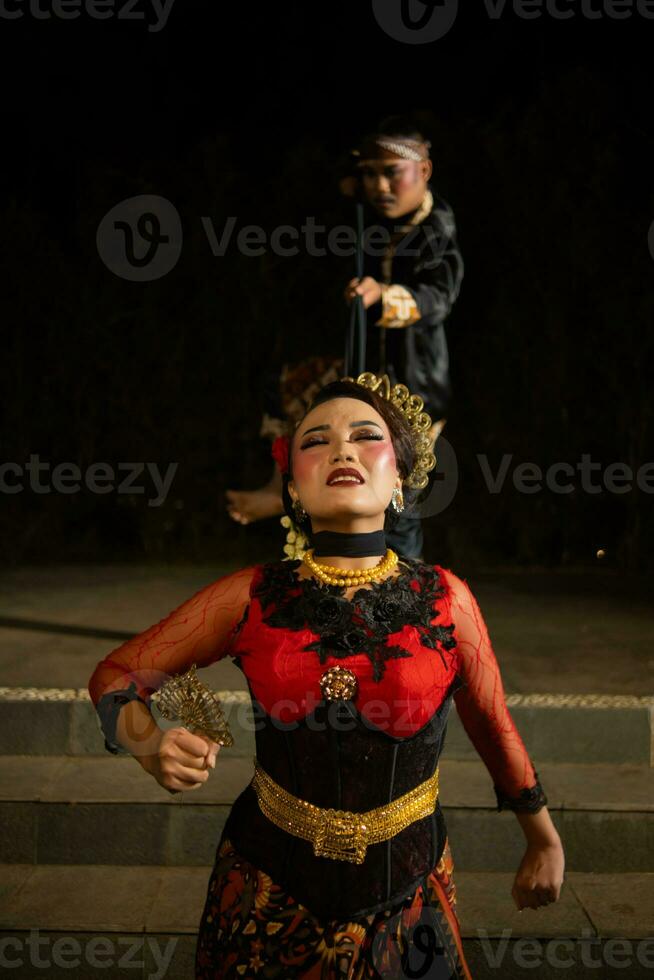 female dancers tied by black scarves while being held by men with sad expressions photo