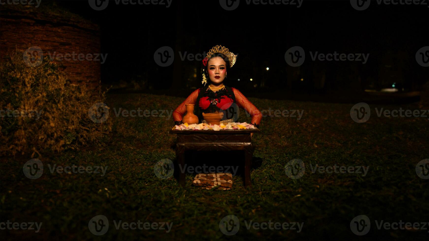 a female dancer who looks beautiful in a red costume performs a ritual that radiates an aura of beauty and purity photo
