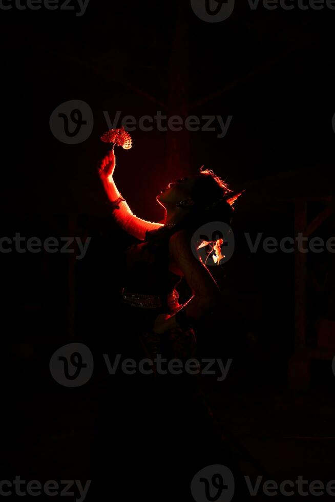 the silhouette of a female dancer holding jewelry that looks like a reflection reflecting in the dim light photo