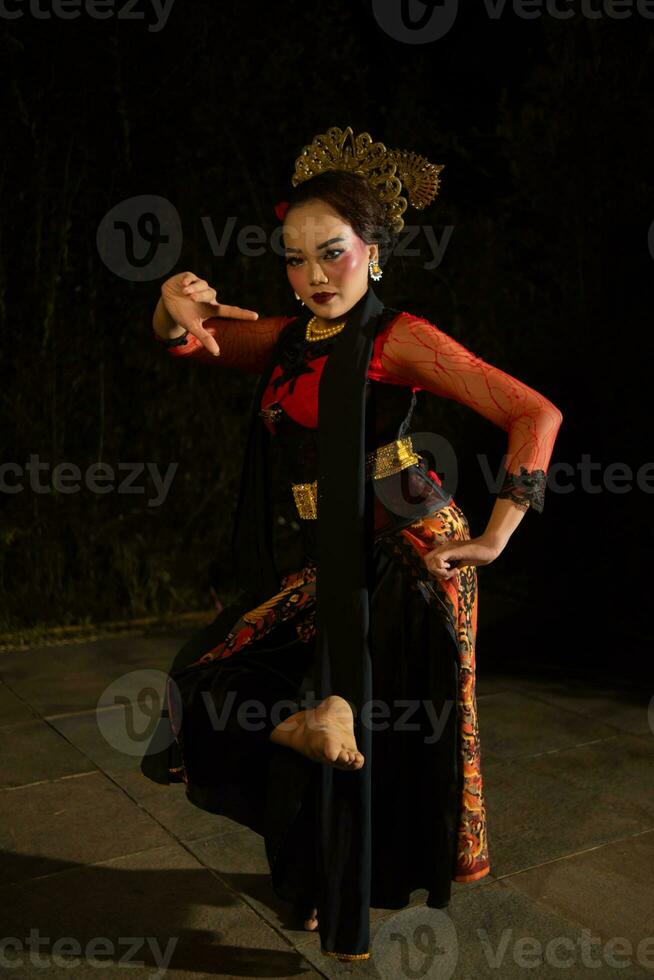 a woman wearing a red dress and black shawl while dancing in front of the audience photo