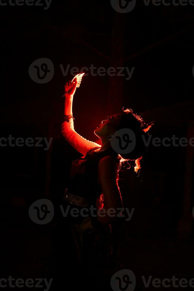 silueta de un hembra bailarín participación joyería en el medio de el quietud de el noche con rojo ligero foto