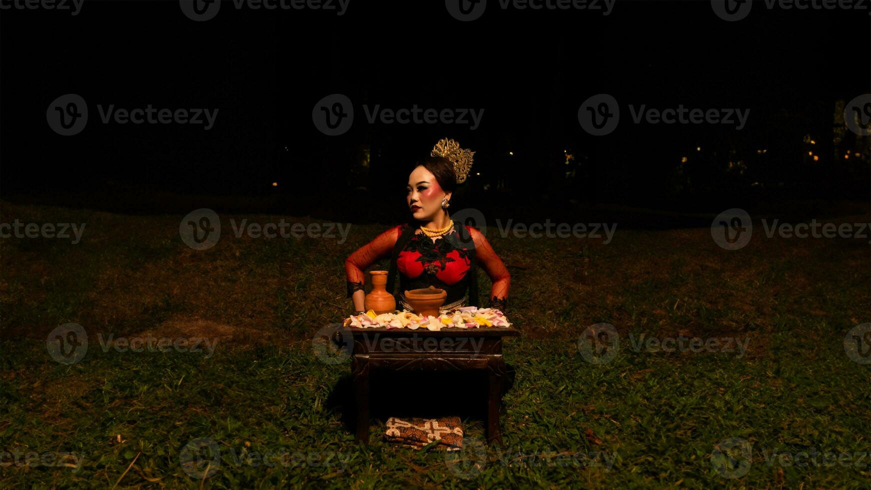 a female dancer performs a ritual that creates a magical and mystical atmosphere in front of flower offerings photo