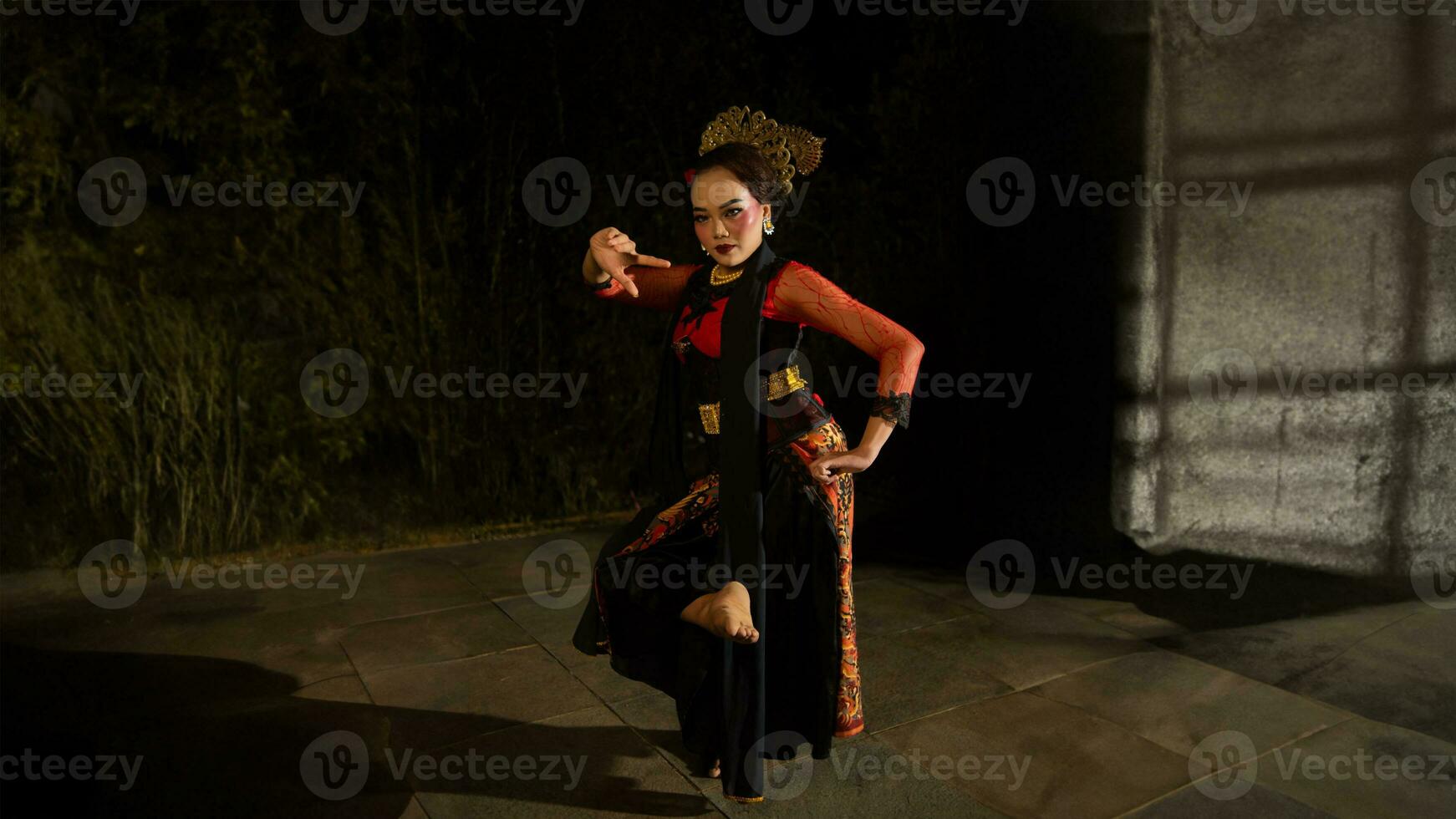 A Sundanese dancer wears a beautiful sparkling red costume and dances with a passionate expression photo