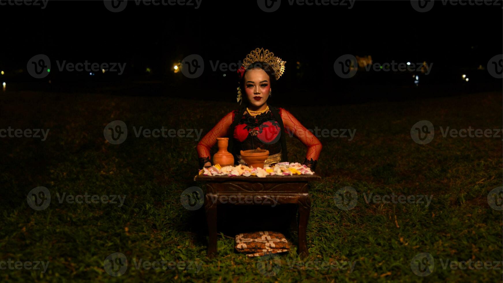 a female dancer looks focused on her ritual with a peaceful facial expression in front of offerings that look fresh and lively photo