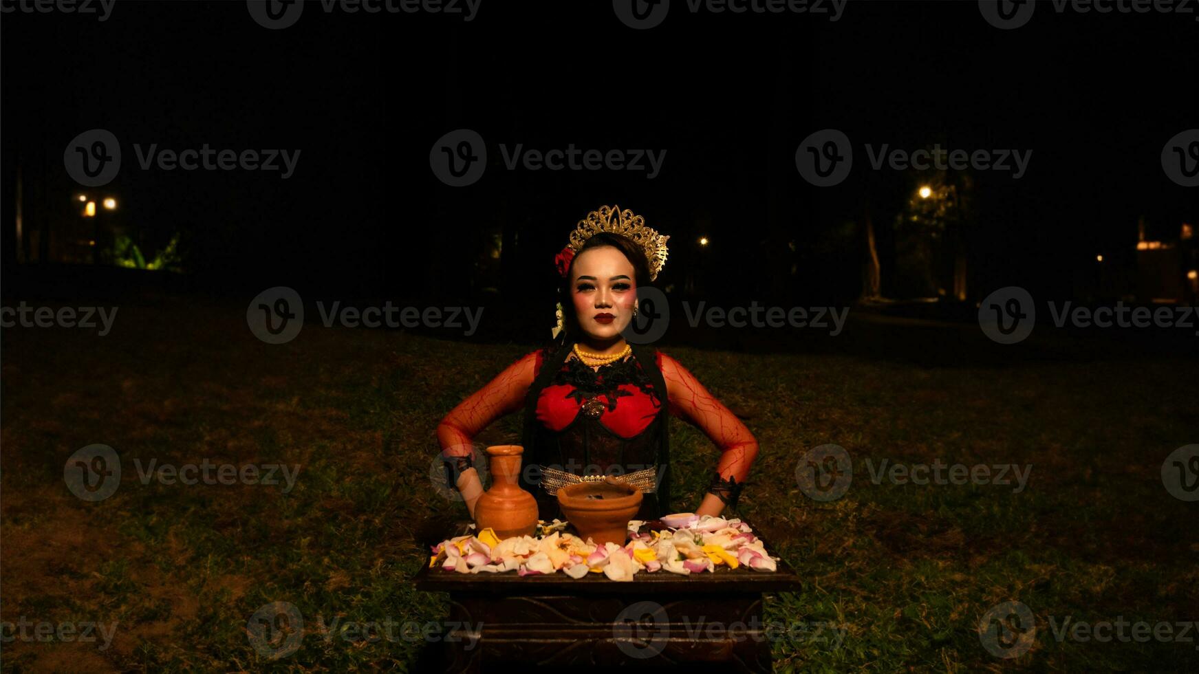 a female dancer performs a ritual that creates a magical and mystical atmosphere in front of flower offerings photo