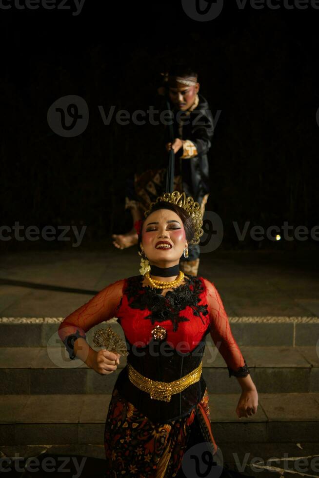 female dancers tied by black scarves while being held by men with sad expressions photo