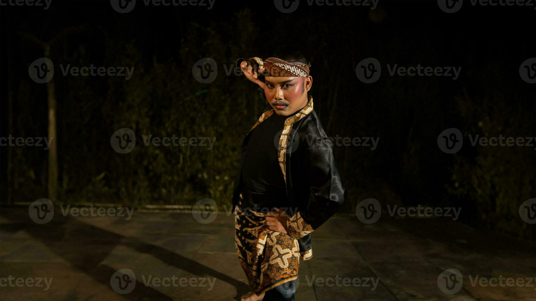 an Indonesian man dances with determination and skill while wearing a black costume on stage photo