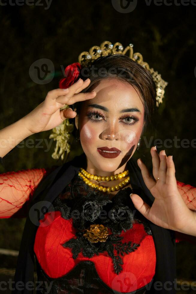 An Indonesian dancer in red clothes and a black scarf poses with very curly and beautiful fingers photo