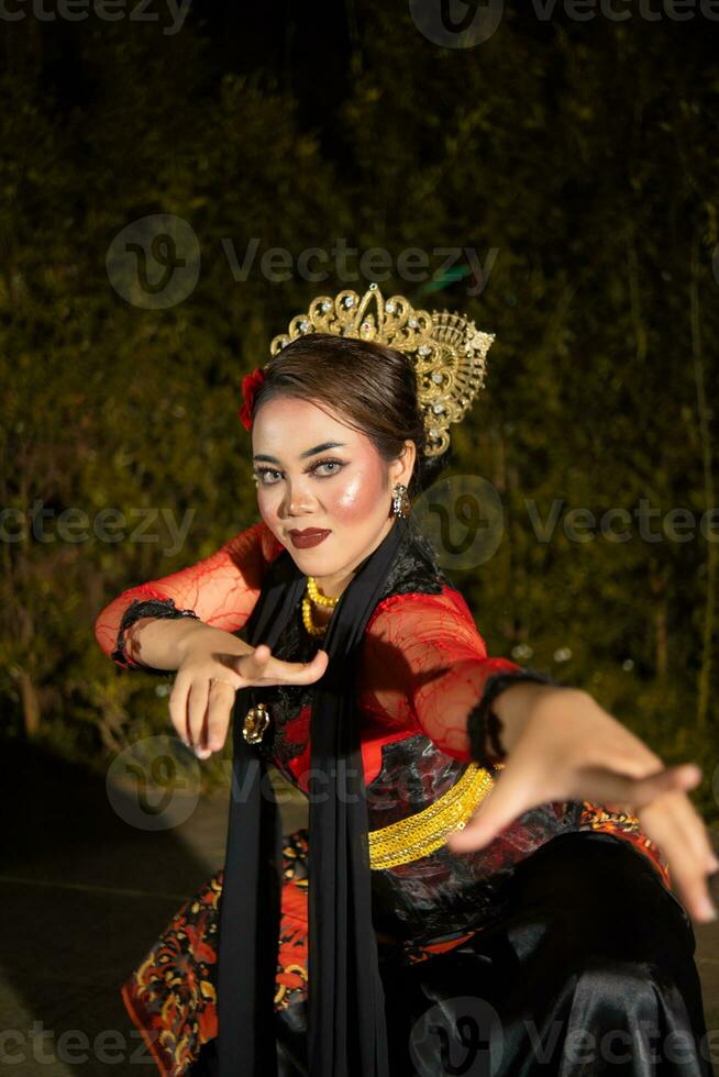 An Asian dancer in a red costume poses very flexibly on a stage photo