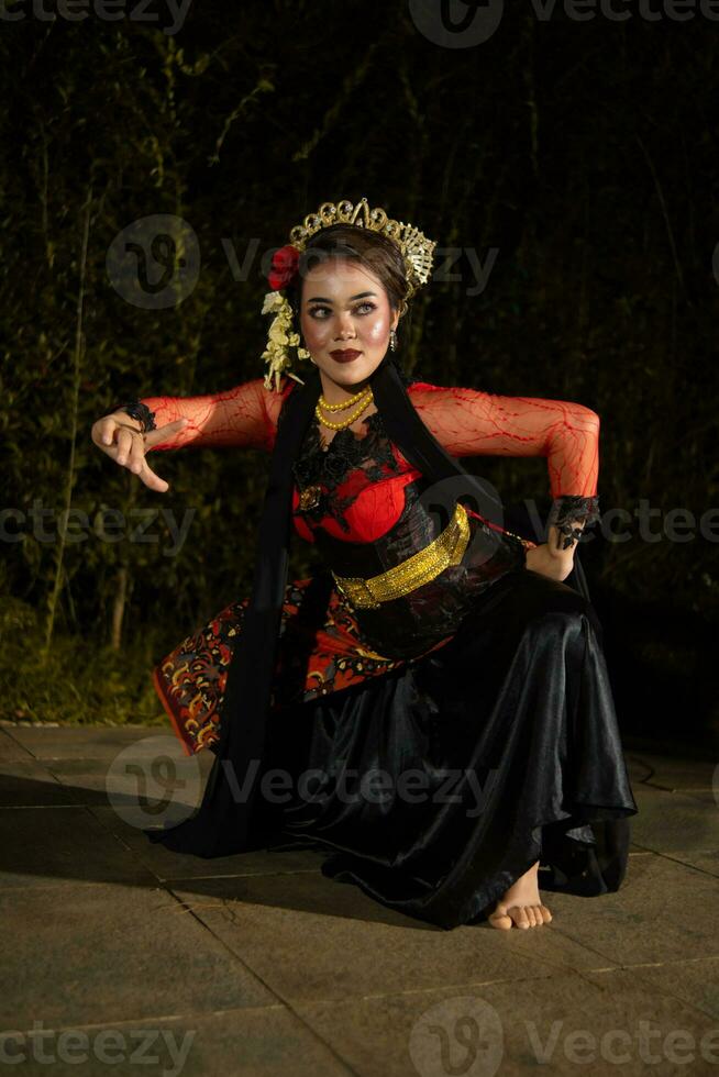 An Asian dancer in a red costume poses very flexibly on a stage photo