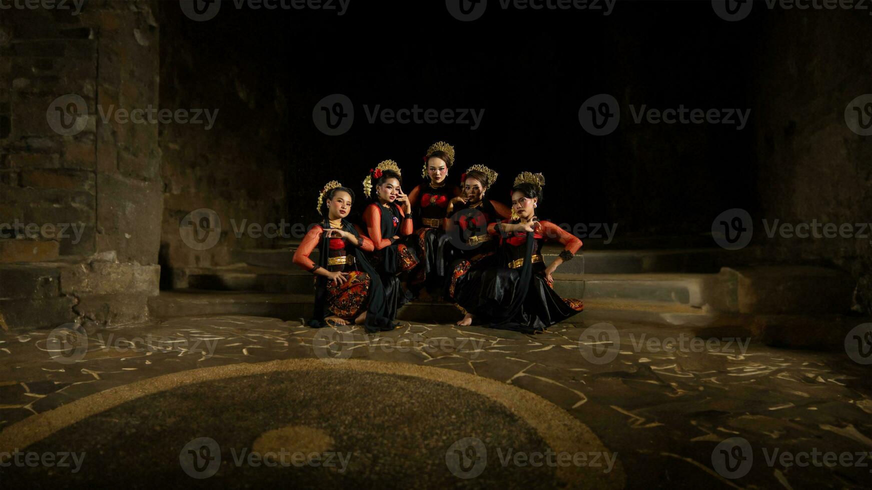 un grupo de indonesio bailarines sentado muy esmeradamente mientras vistiendo rojo vestidos en un castillo foto