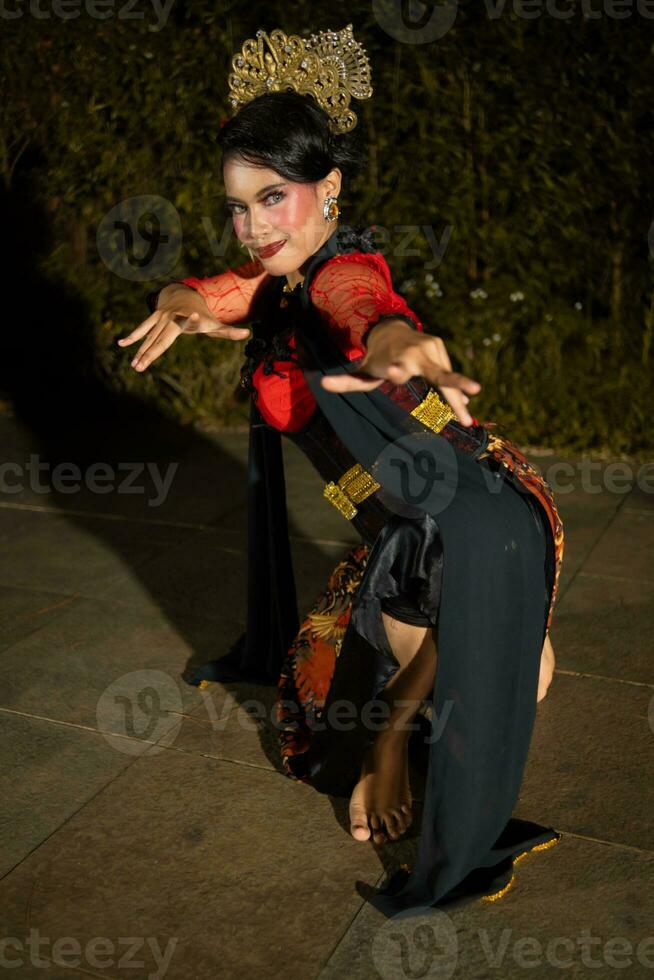 a Javanese dancer dancing with gold accessories and a face full of makeup photo