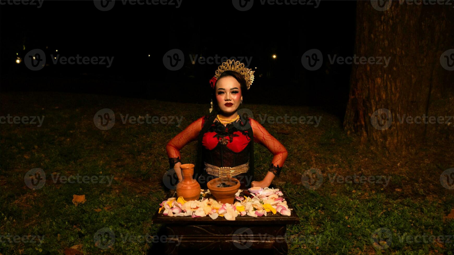 a female dancer performs a ritual that creates a magical and mystical atmosphere in front of flower offerings photo