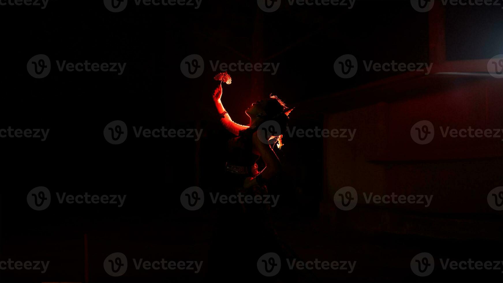 the silhouette of a female dancer holding jewelry that looks like a reflection reflecting in the dim light photo