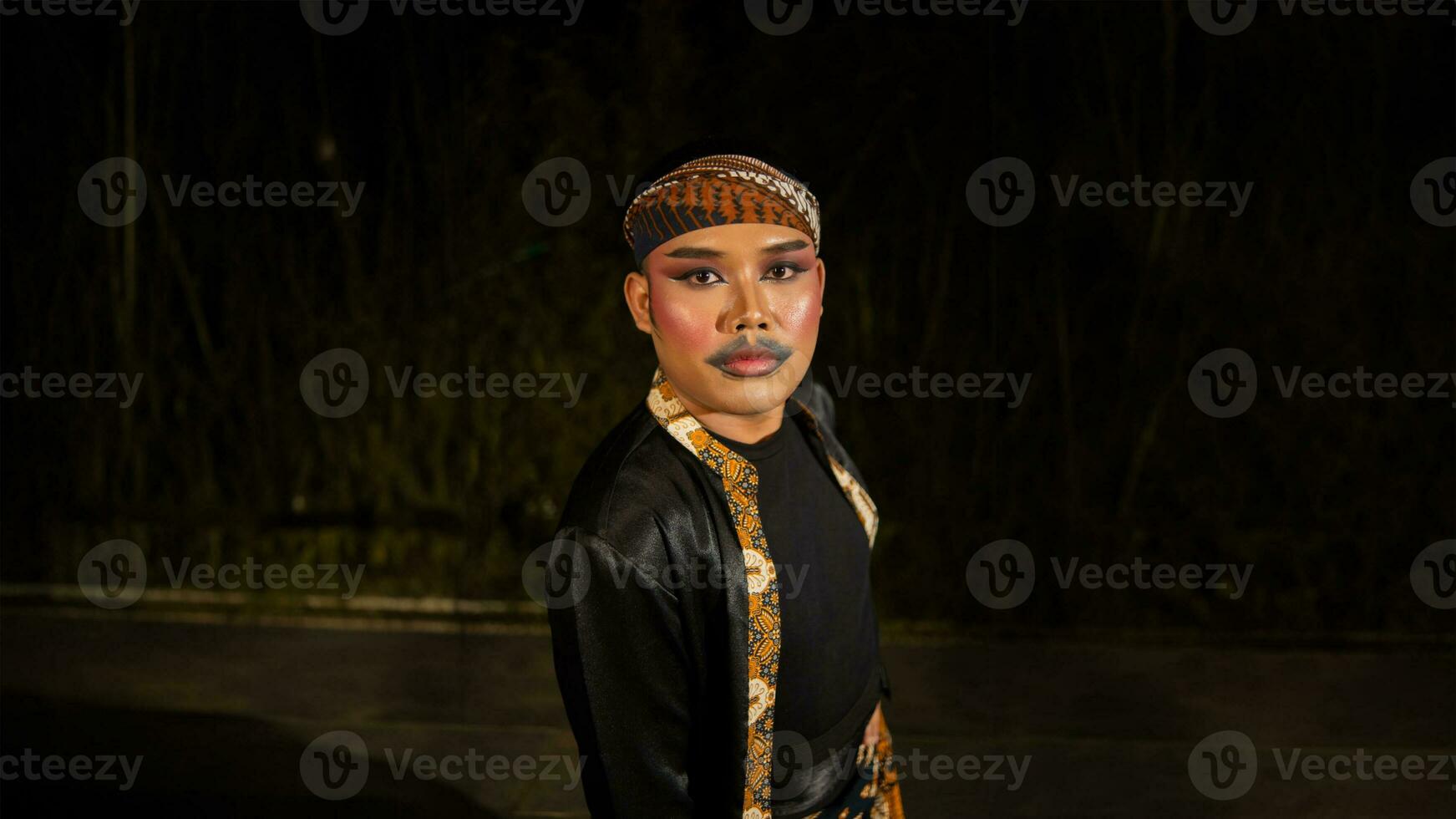 an Indonesian man dances with determination and skill while wearing a black costume on stage photo