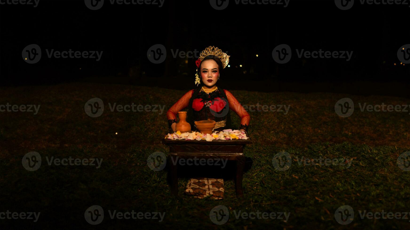 un hembra bailarín mira enfocado en su ritual con un pacífico facial expresión en frente de ofrendas ese Mira Fresco y animado foto