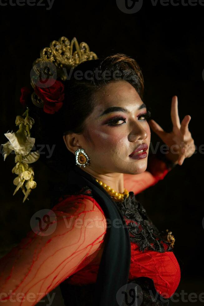 cerca arriba de un indonesio mujer en un balinés bailarín disfraz posando muy hermosamente a noche foto