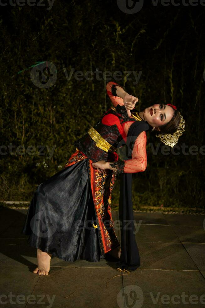 a Javanese dancer dances in front of the audience with an agile body in a black costume photo