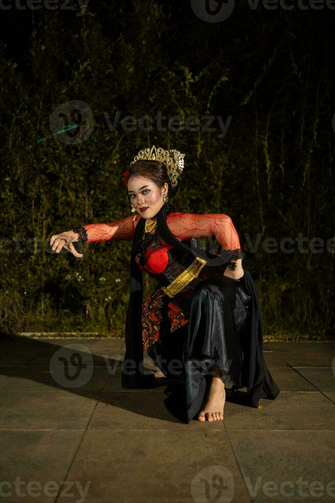 An Asian dancer in a red costume poses very flexibly on a stage photo