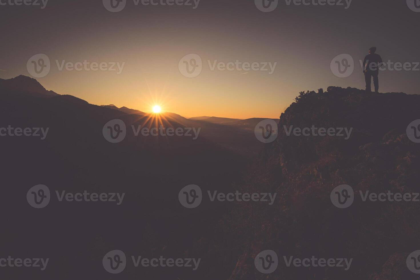 Hiker on a mountain top at sunset. Woman admiring mountain landscape in High Tatra Mountains, Poland. photo