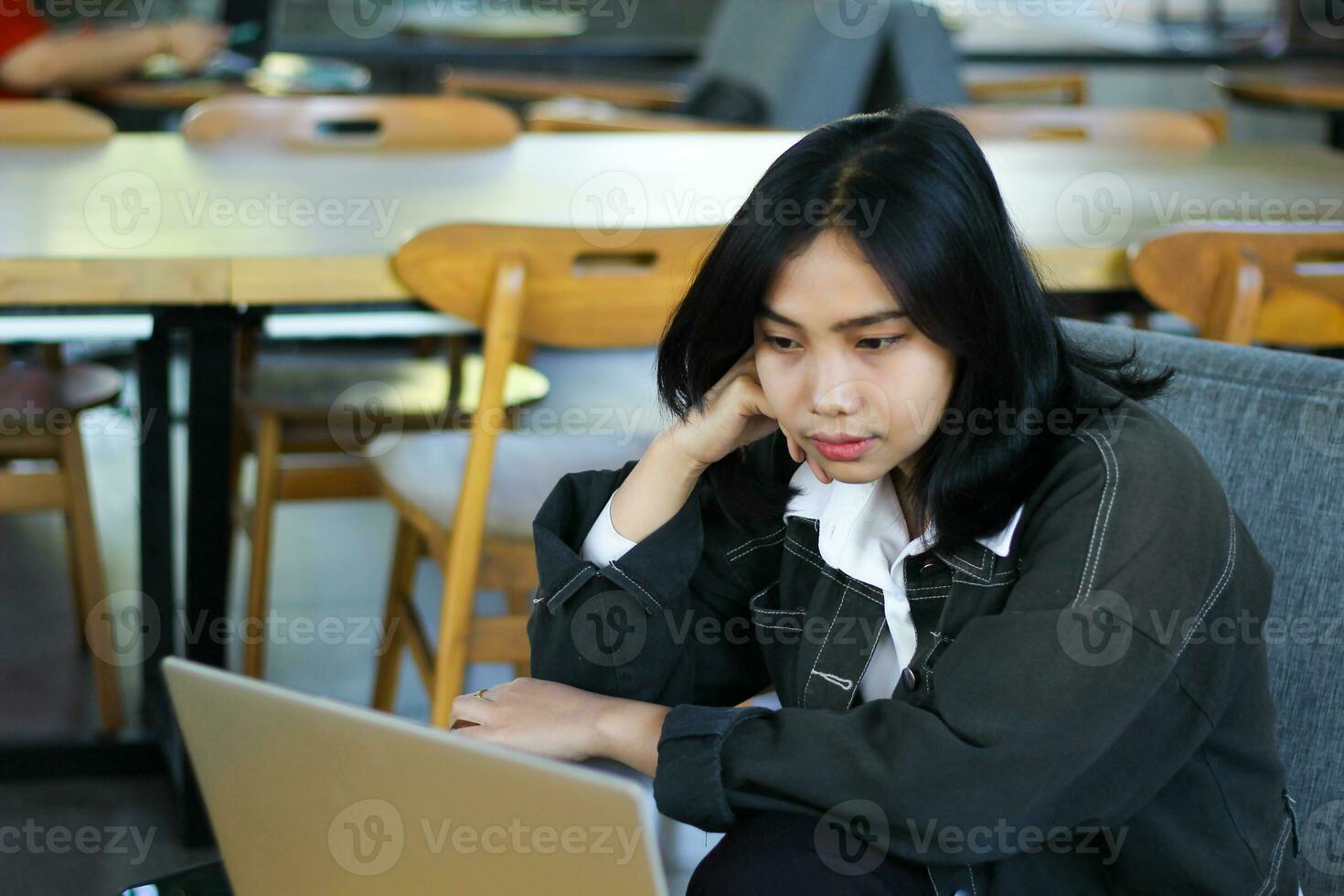 beautiful asian woman look bored using laptop in cafe, working remotely photo