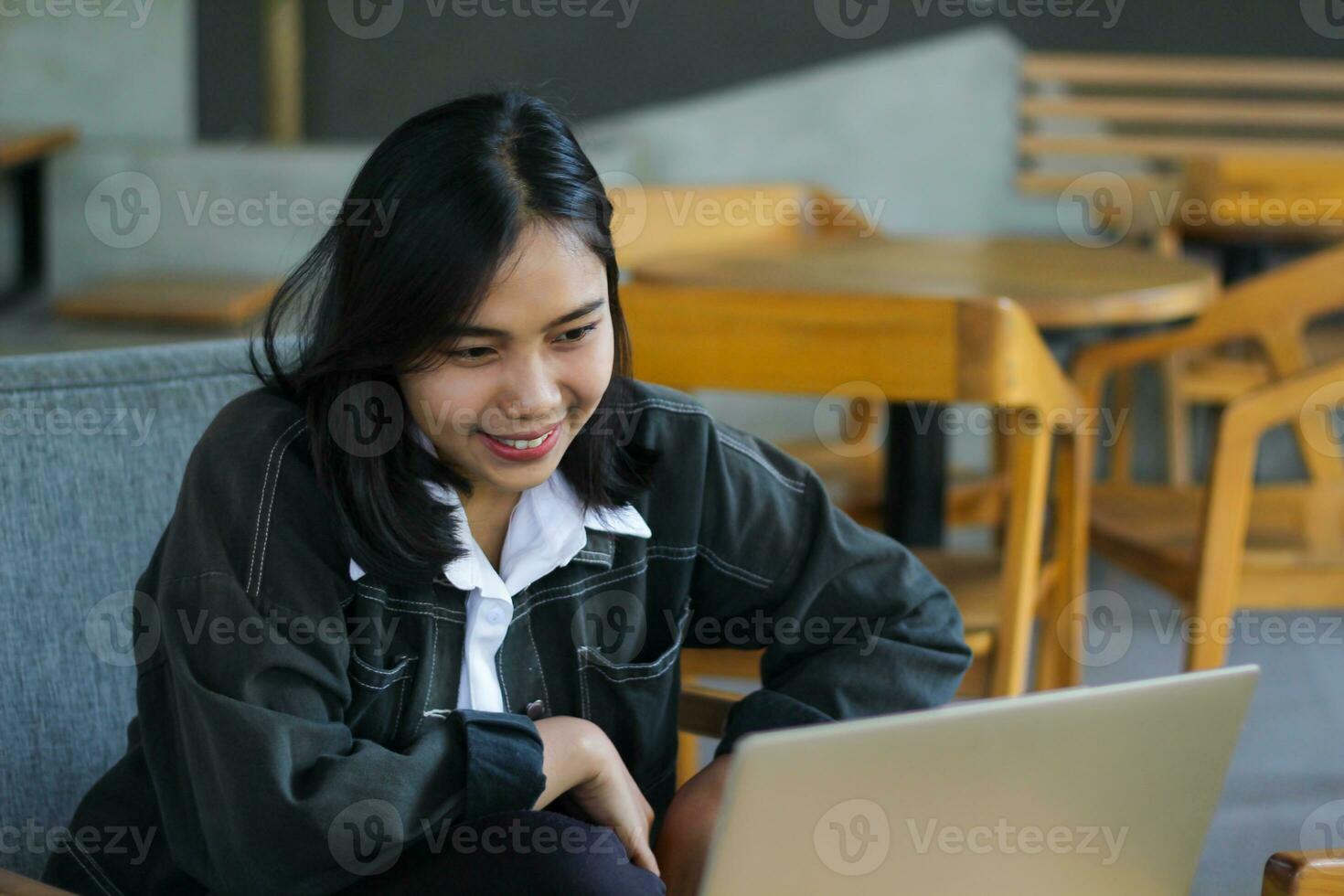 cheerful asian woman using laptop to have online meeting video conference in indoor cafe photo