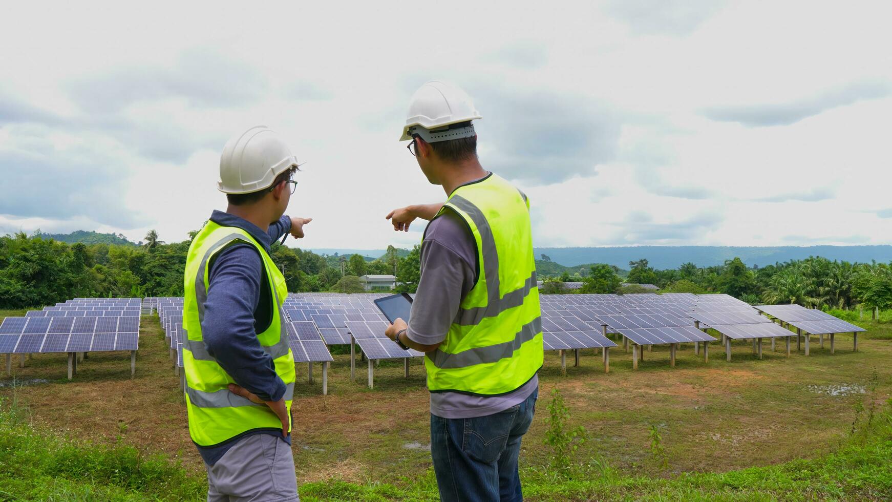 Professional asian man engineer using digital tablet maintaining solar cell panels together .Technician team working on ecological solar farm. photo