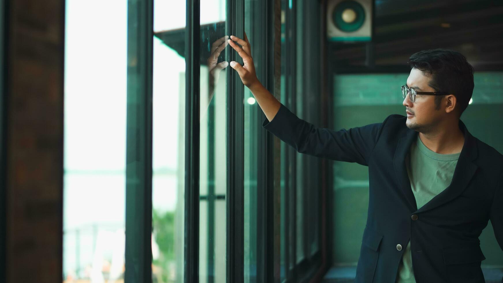 Handsome 38 years old gentle asian  man, wearing glasses, formal slick hairstyle,  in a modern office building beside a huge window photo