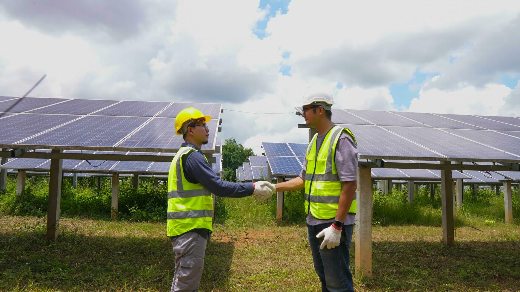 Two asian engineers shaking hands after  installing solar panels . Solar energy clean and green alternative energy. Unity and teamwork. photo