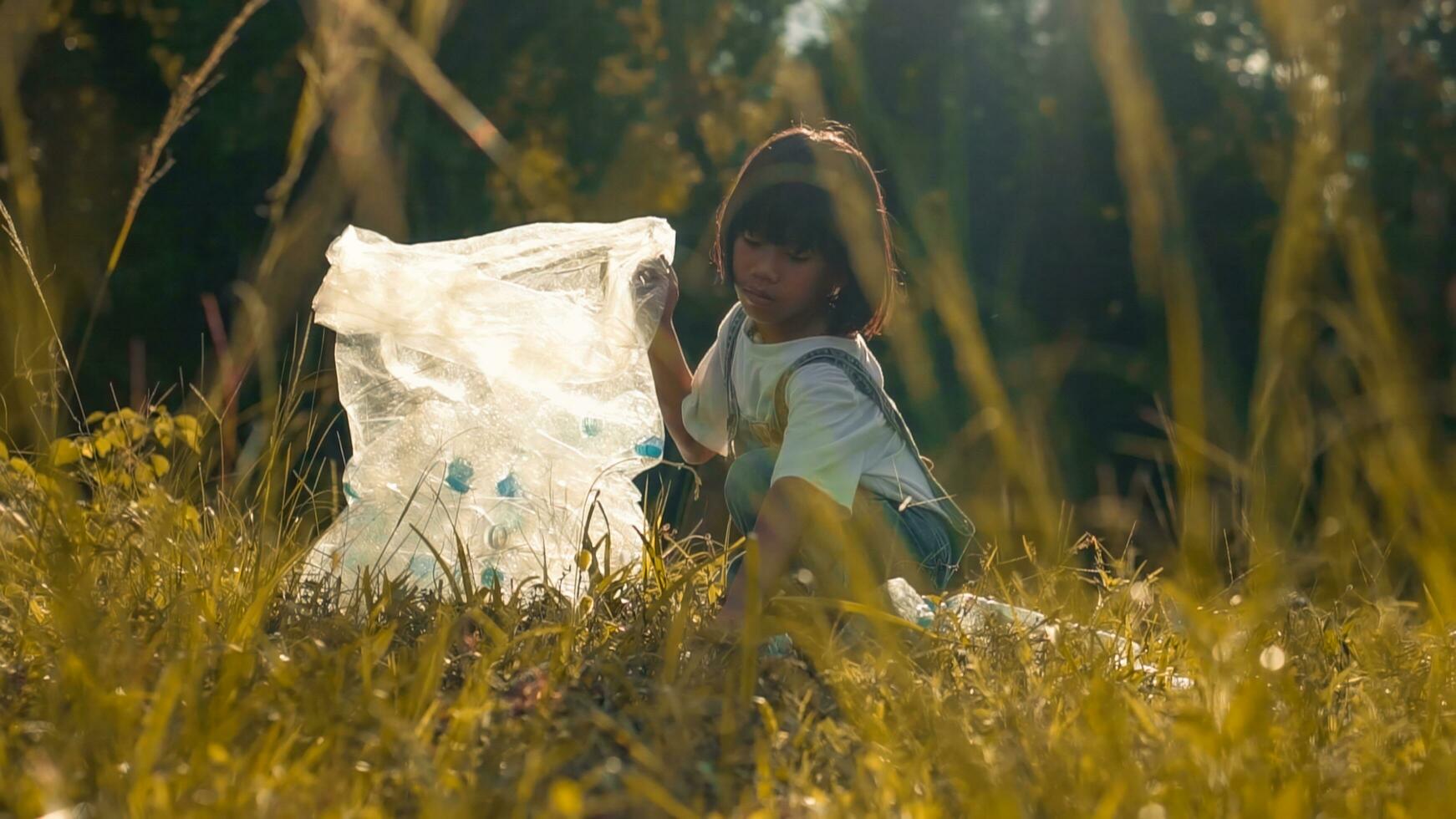 Kid Girl  collection plastic garbage in nature. kid picking up trash in park. photo