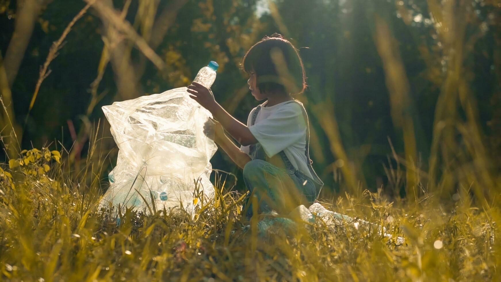 Kid Girl  collection plastic garbage in nature. kid picking up trash in park. photo