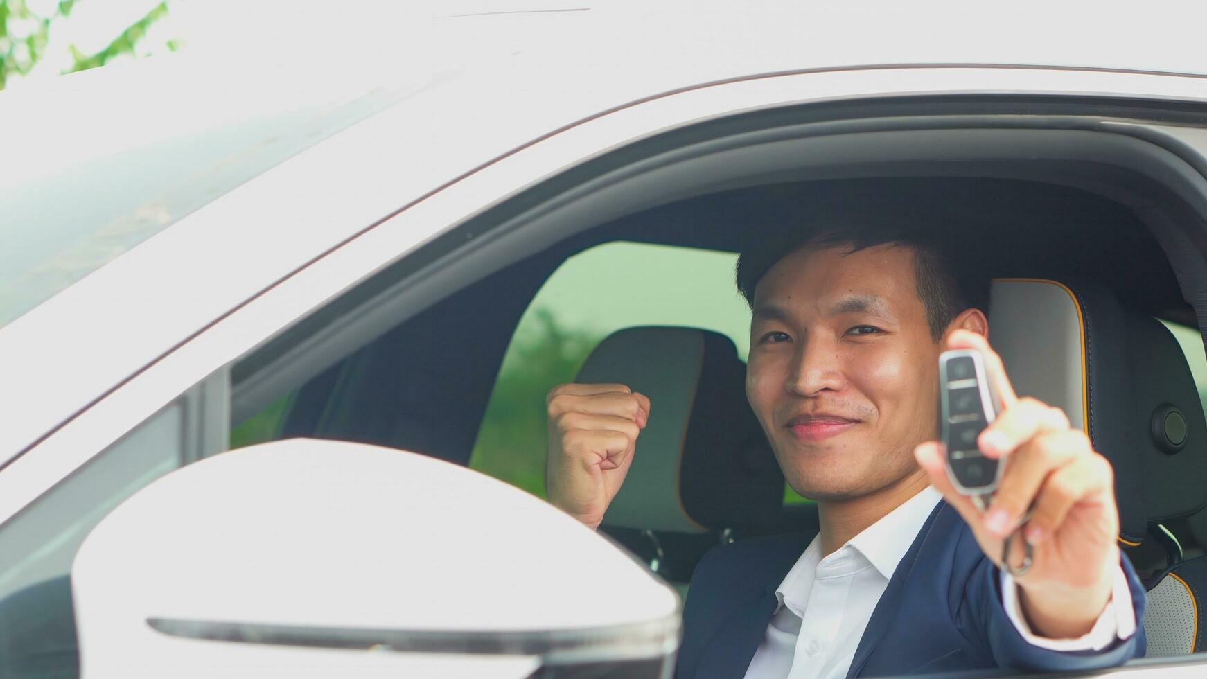 Young asian businessman showing a car key inside his new electric vehicle. EV Car. photo