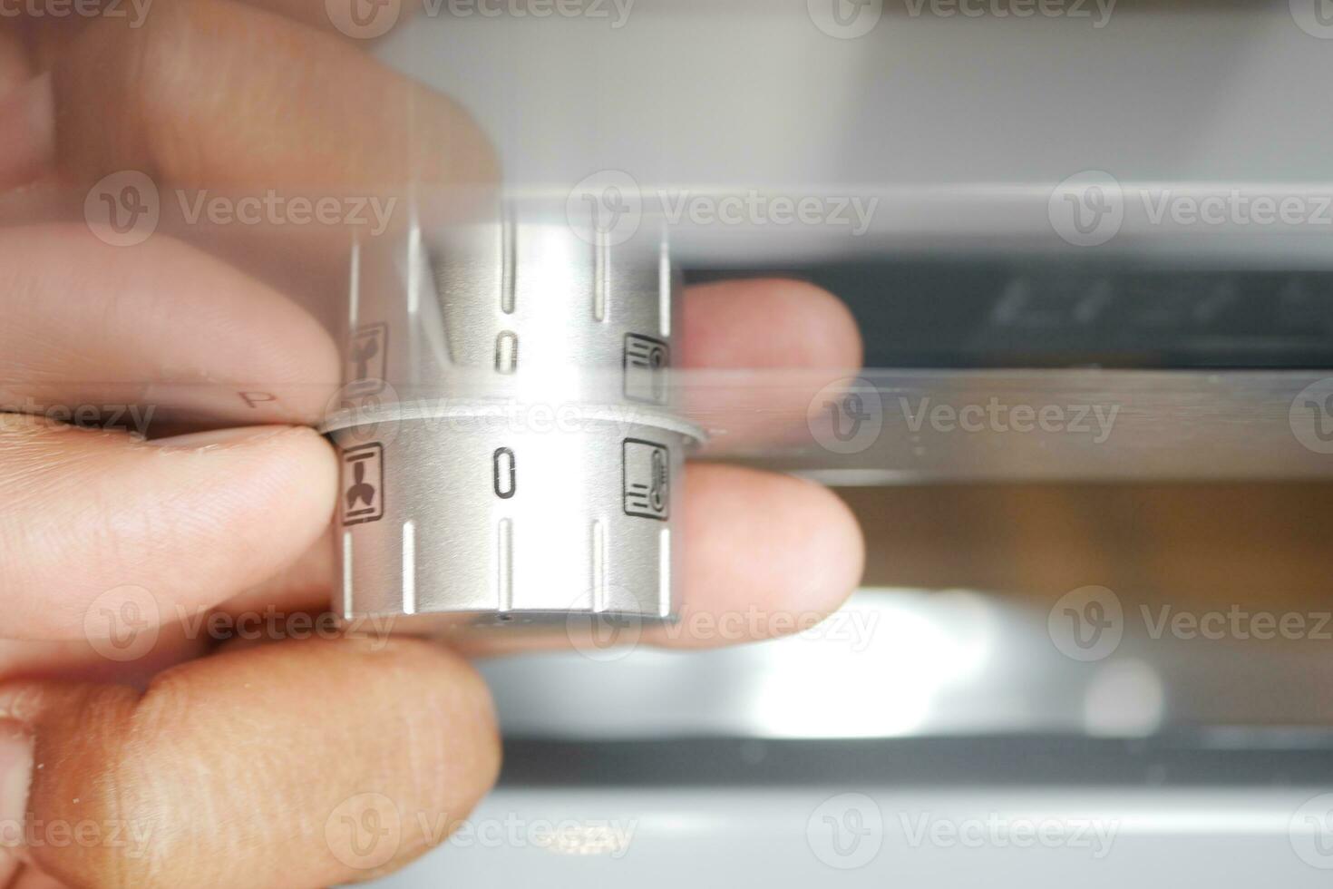 Close up of men hand setting temperature control on oven. photo
