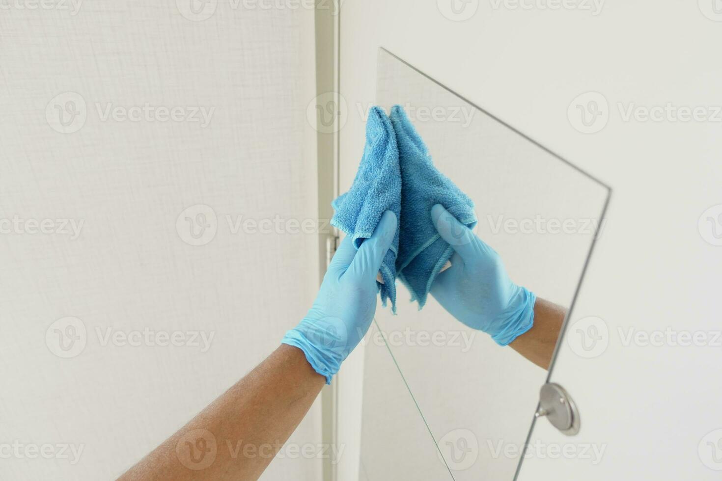 close up of person hand in gloves cleaning window glass photo