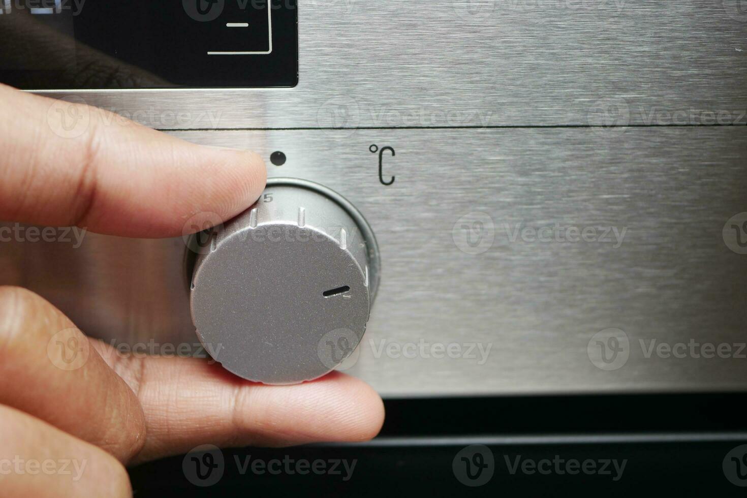 Close up of men hand setting temperature control on oven. photo