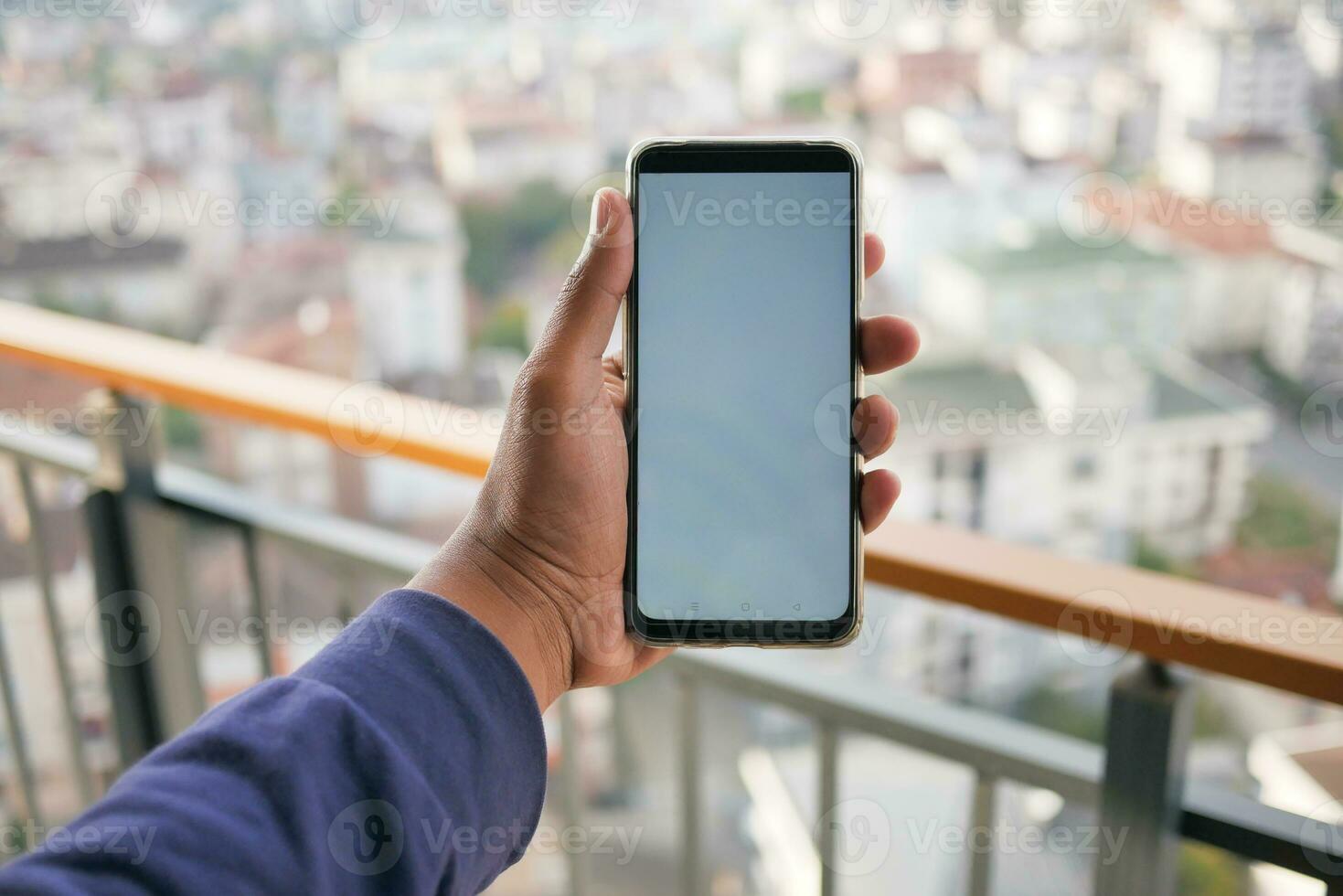 young man hand using smart phone with green screen against city buildings photo