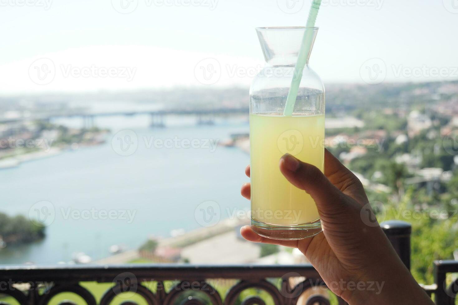 holding a glass of orange juice against blue sky photo