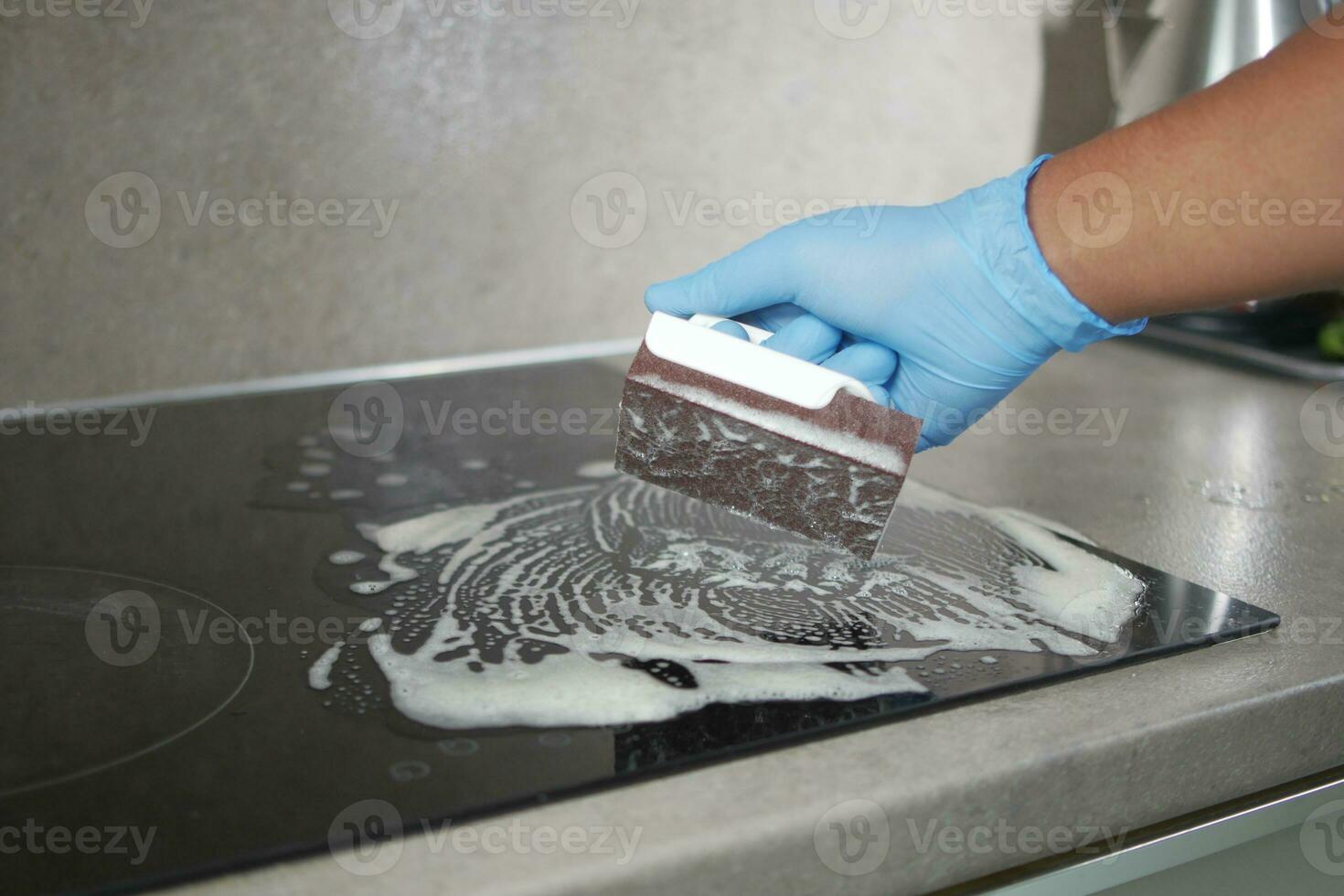 Top view Cleaning a ceramic electric stove with a metal scraper. photo